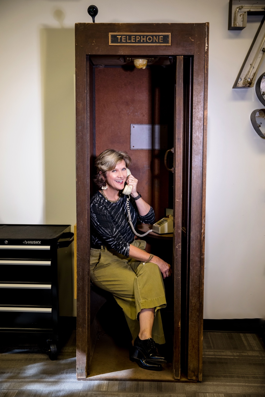 Lynn Yeldell smiling in a vintage telephone booth