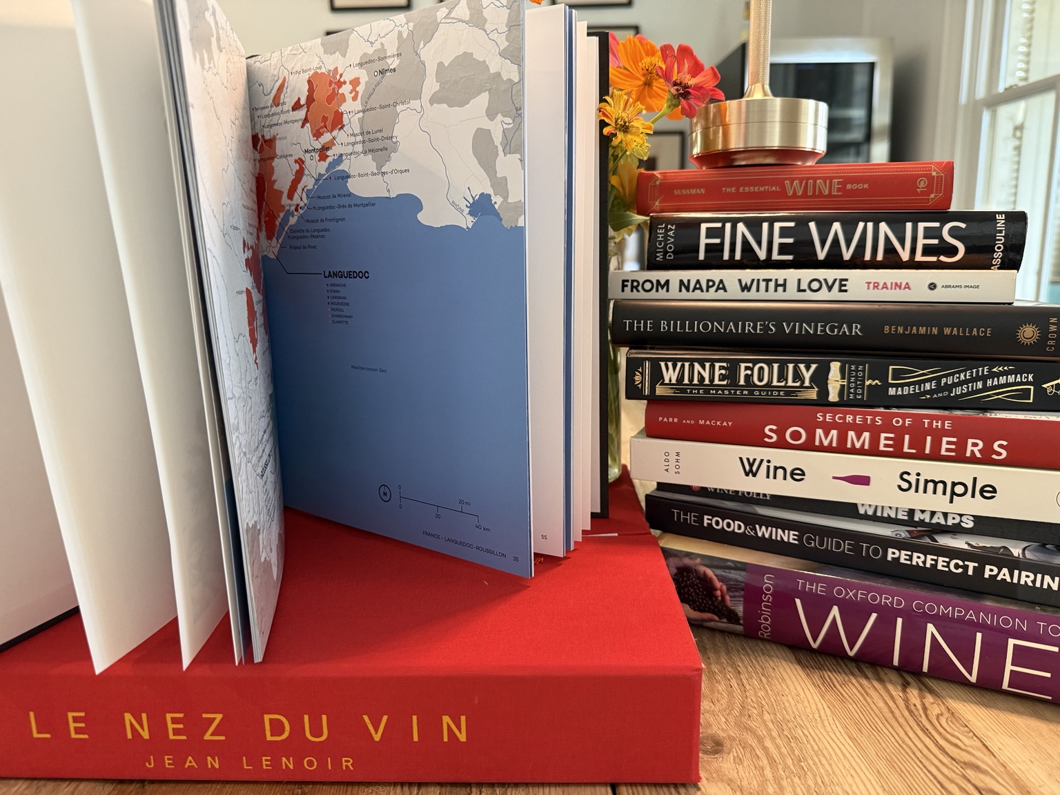 An open wine atlas beside a personal collection of wine books