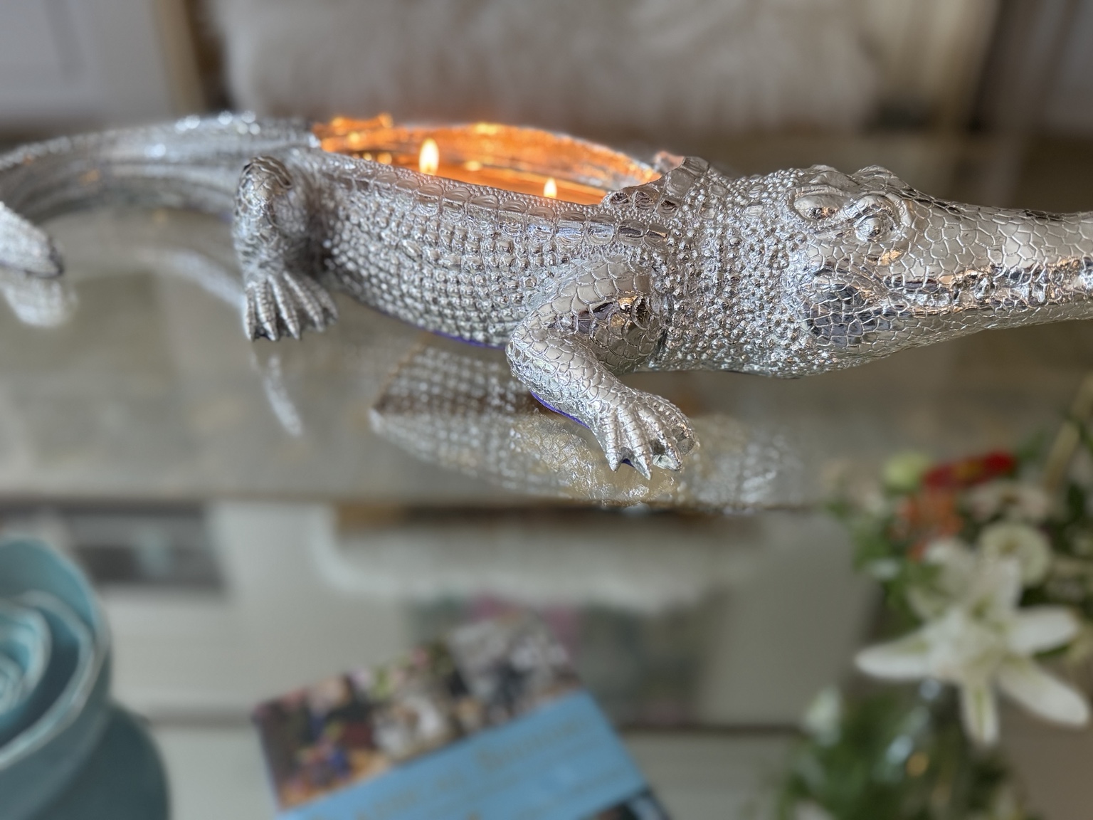 A lit silver alligator-shaped Thompson Ferrier candle